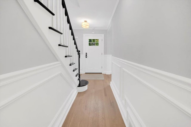 6 Mcbride Ave, White Plains, NY 10603 - doorway to outside featuring a decorative wall, crown molding, stairway, a wainscoted wall, and light wood-style flooring
