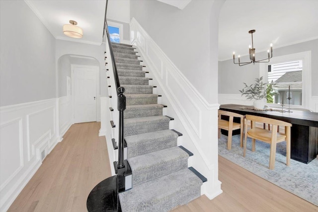 6 Mcbride Ave, White Plains, NY 10603 - staircase featuring arched walkways, a chandelier, wood finished floors, crown molding, and a wainscoted wall