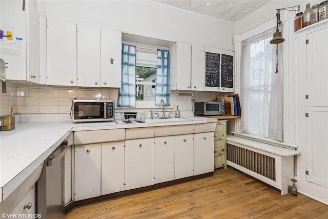 24 John St, Beacon, NY 12508 - kitchen featuring appliances with stainless steel finishes, a sink, light countertops, white cabinetry, and light wood finished floors