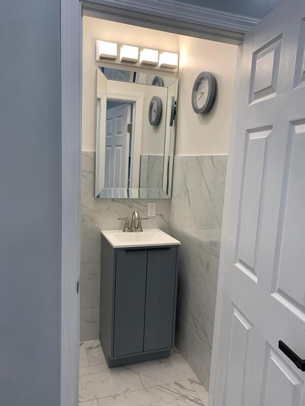 158-04 111th Ave, Jamaica, NY 11433 - bathroom featuring marble look tiles, vanity, tile walls, and wainscoting