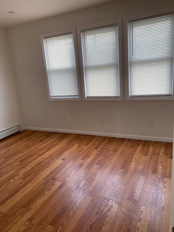 158-04 111th Ave, Jamaica, NY 11433 - spare room with wood finished floors, baseboards, and a baseboard heating unit