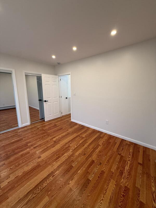 158-04 111th Ave, Jamaica, NY 11433 - unfurnished bedroom featuring multiple closets, wood finished floors, baseboards, and recessed lighting