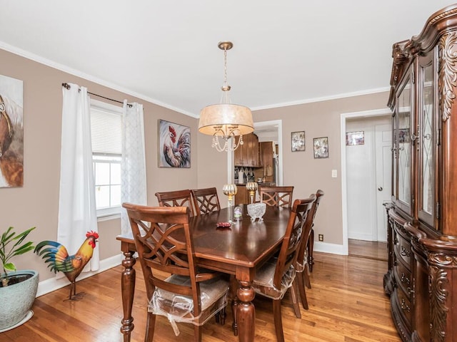 dining room featuring baseboards, light wood-style floors, and ornamental molding