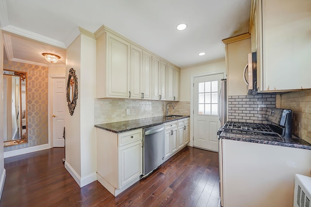 kitchen with stainless steel appliances, dark wood-style flooring, a sink, ornamental molding, and dark stone counters