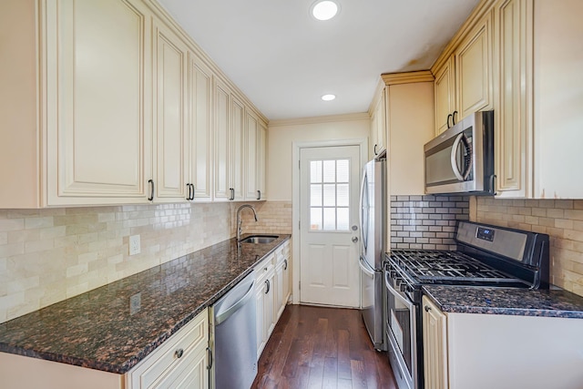 kitchen featuring stainless steel appliances, a sink, dark wood-style floors, dark stone counters, and decorative backsplash