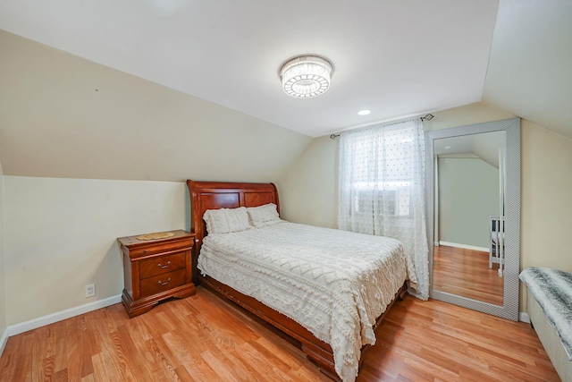 bedroom featuring light wood-type flooring, vaulted ceiling, and baseboards