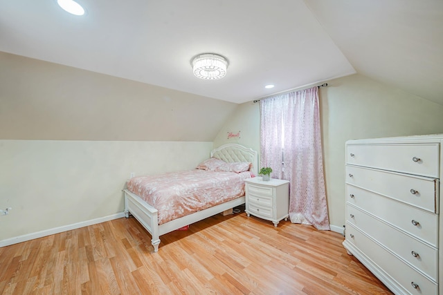 bedroom with vaulted ceiling, light wood-style floors, and baseboards