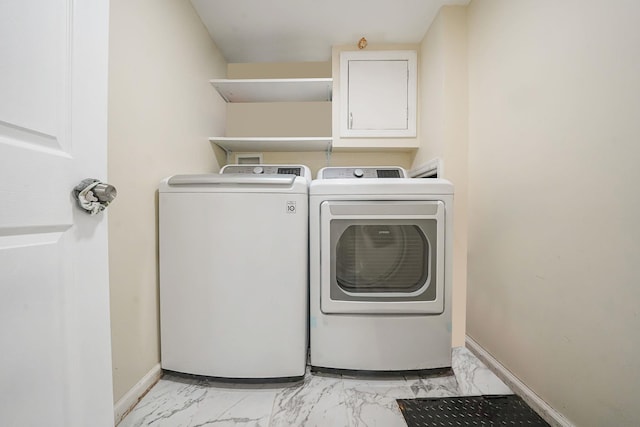 laundry room with light marble finish floors, washing machine and dryer, and baseboards