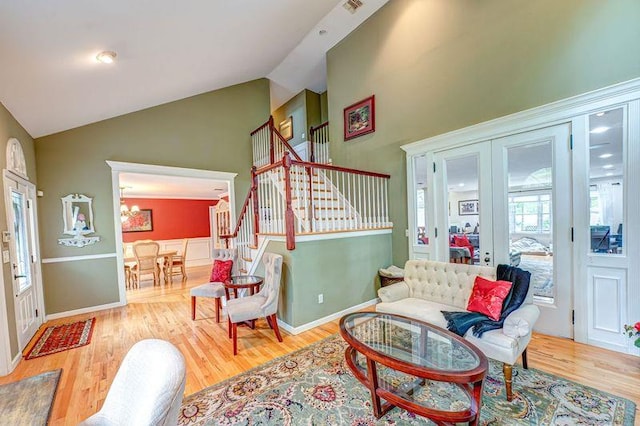 living area with high vaulted ceiling, stairway, wood finished floors, and baseboards