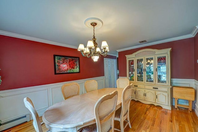 dining space with a baseboard radiator, a chandelier, crown molding, light wood finished floors, and a wainscoted wall