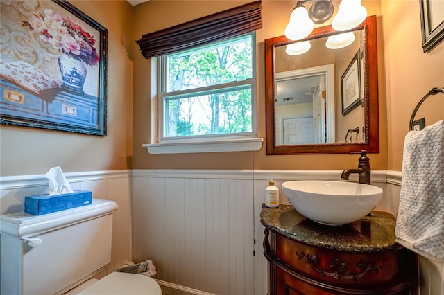 half bathroom featuring a wainscoted wall, vanity, and toilet
