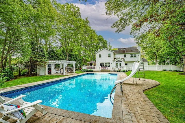 view of swimming pool featuring a pergola, a water slide, a patio area, and view of wooded area