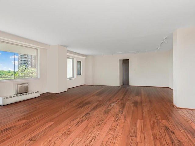unfurnished room featuring rail lighting, a baseboard radiator, light wood-style floors, and healthy amount of natural light