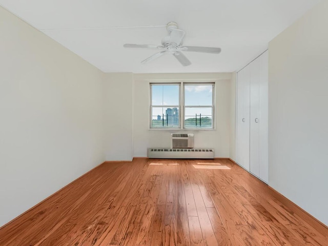 empty room with hardwood / wood-style floors, baseboard heating, and a ceiling fan