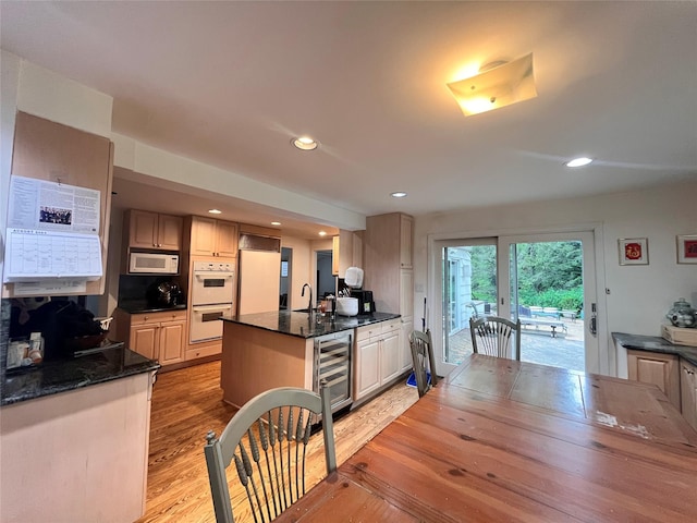 kitchen with beverage cooler, white appliances, a sink, light wood-style floors, and recessed lighting