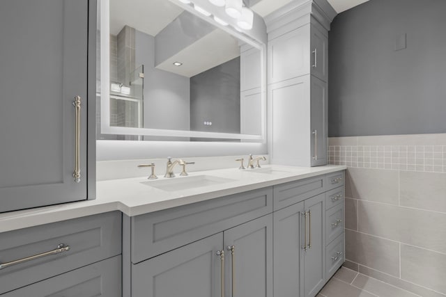 bathroom with tile walls, double vanity, tile patterned floors, and wainscoting