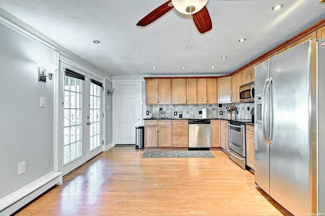 kitchen featuring stainless steel appliances, baseboard heating, tasteful backsplash, light wood-type flooring, and ceiling fan