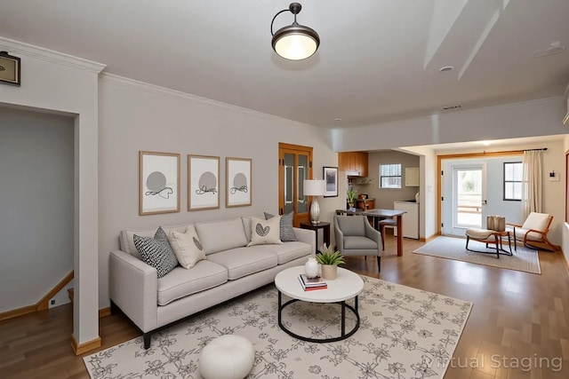 living area featuring wood finished floors, crown molding, washer / clothes dryer, and baseboards