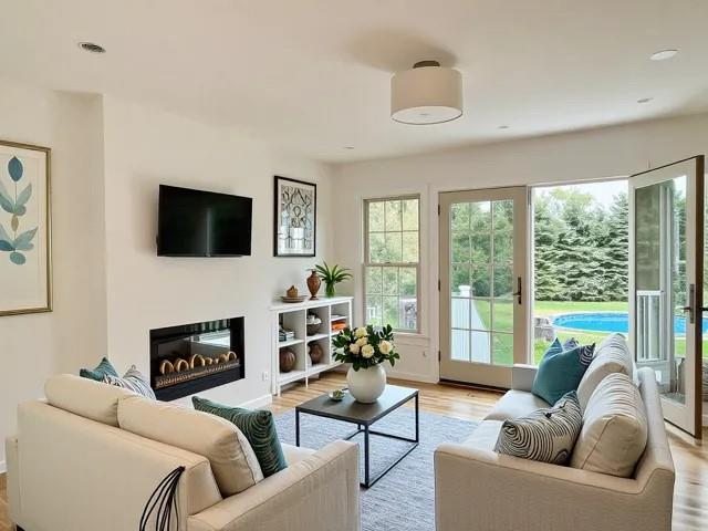 2850 Reeve Rd, Mattituck, NY 11952 - living area with light wood-style floors, healthy amount of natural light, a glass covered fireplace, recessed lighting, and baseboards