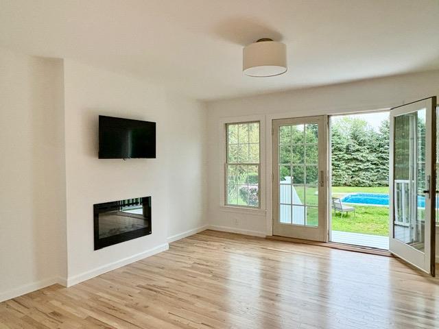 2850 Reeve Rd, Mattituck, NY 11952 - unfurnished living room with wood finished floors, baseboards, and a glass covered fireplace