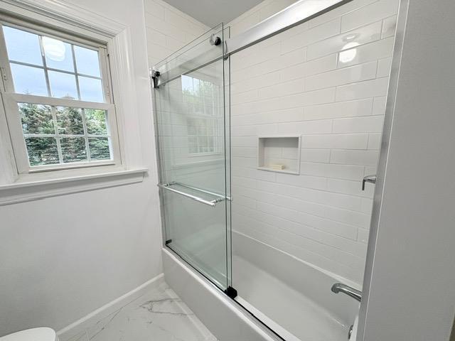 2850 Reeve Rd, Mattituck, NY 11952 - bathroom featuring marble look tile flooring, baseboards, shower / bath combination with glass door, and toilet
