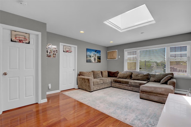 living area featuring a skylight, wood finished floors, baseboards, recessed lighting, and baseboard heating