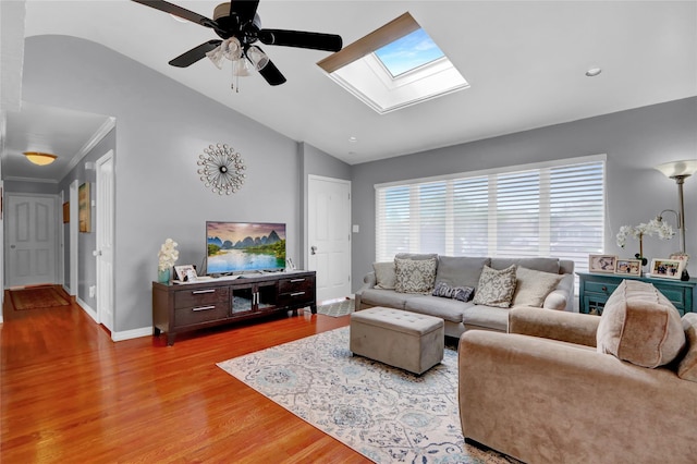 living room with lofted ceiling, a skylight, a ceiling fan, wood finished floors, and baseboards