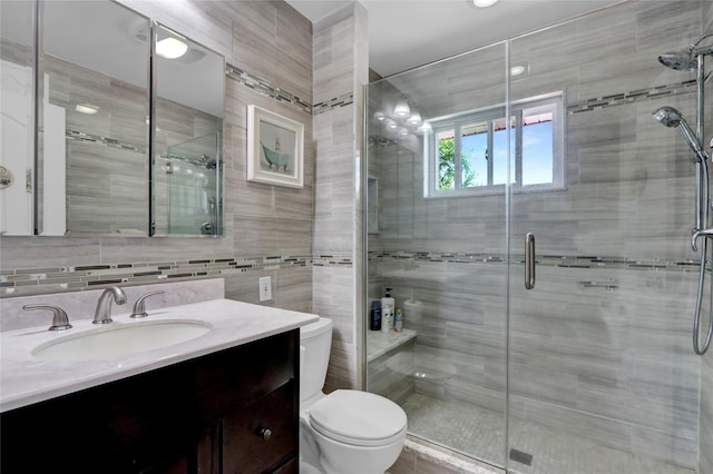 bathroom with toilet, vanity, and a shower stall