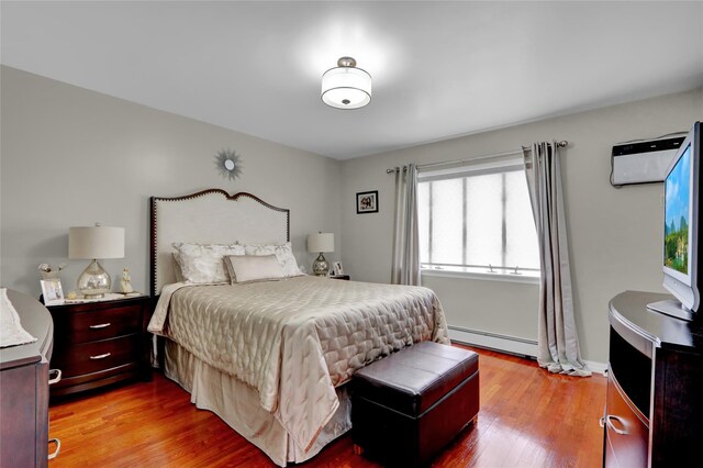 bedroom with a baseboard radiator and light wood finished floors