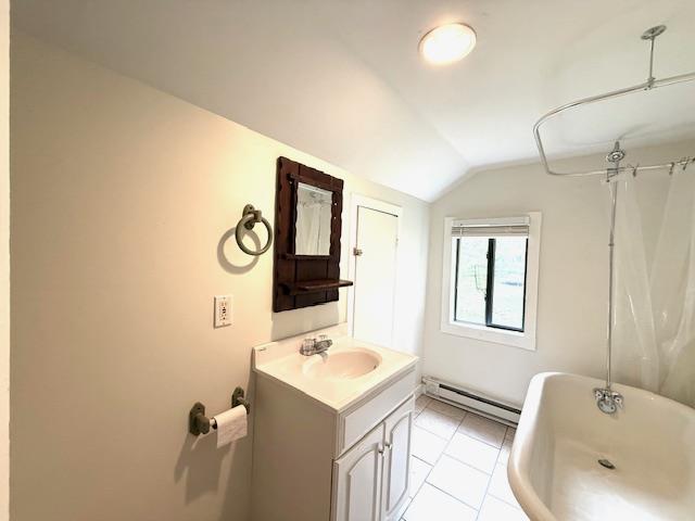 38 Eldred Yulan Rd, Eldred, NY 12732 - full bath with a baseboard radiator, vaulted ceiling, a soaking tub, vanity, and tile patterned floors