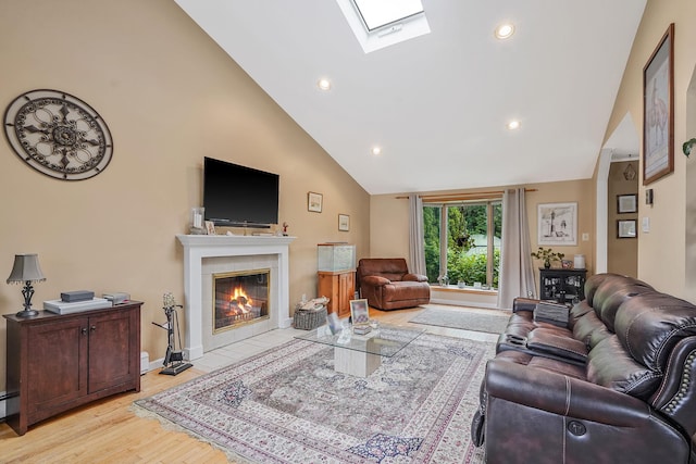 27 Amby Ave, Plainview, NY 11803 - living area with high vaulted ceiling, a tiled fireplace, a skylight, light wood-style floors, and recessed lighting