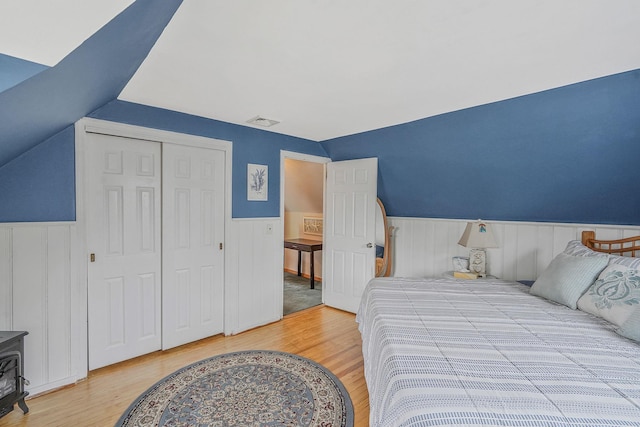 27 Amby Ave, Plainview, NY 11803 - bedroom with light wood-type flooring, wainscoting, lofted ceiling, a closet, and a wood stove