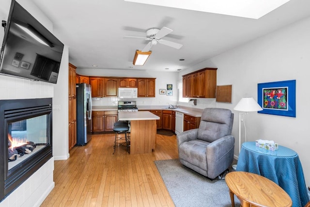 30 Julia Cir, Middle Island, NY 11953 - kitchen with stainless steel appliances, a kitchen breakfast bar, light countertops, brown cabinets, and light wood-type flooring