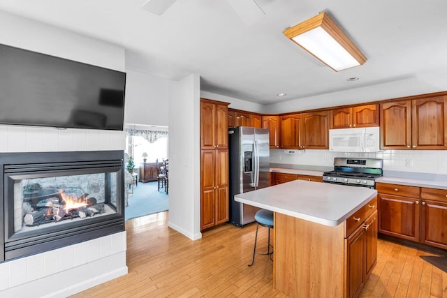 30 Julia Cir, Middle Island, NY 11953 - kitchen with appliances with stainless steel finishes, a kitchen island, light wood-type flooring, light countertops, and brown cabinetry