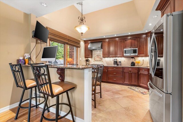 26 Tioga Dr, Jericho, NY 11753 - kitchen featuring stainless steel appliances, wall chimney range hood, dark stone countertops, a peninsula, and a kitchen bar