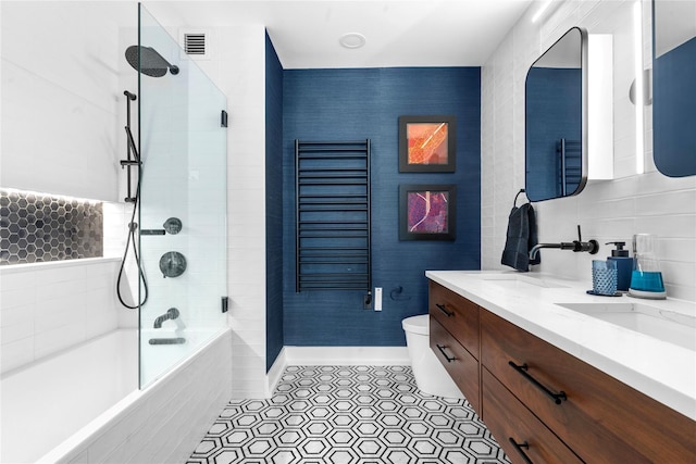 bathroom with tiled shower / bath, double vanity, toilet, tile patterned flooring, and baseboards