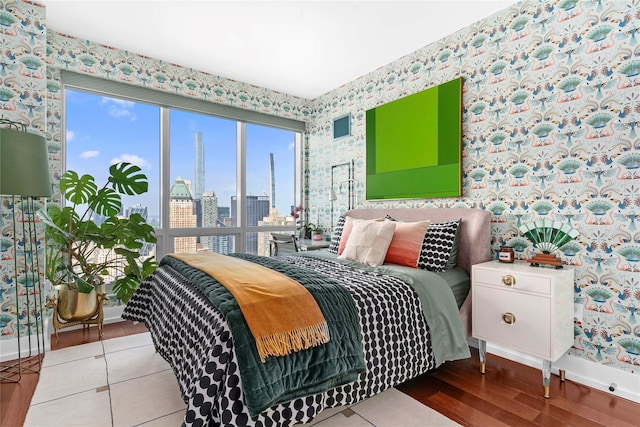 bedroom featuring wallpapered walls, wood finished floors, baseboards, and a view of skyline