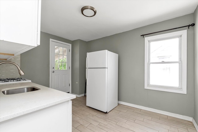 119-64 177th St, Saint Albans, NY 11434 - kitchen featuring freestanding refrigerator, baseboards, backsplash, white cabinets, and light wood-type flooring