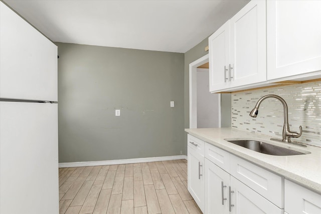 119-64 177th St, Saint Albans, NY 11434 - kitchen with a sink, freestanding refrigerator, tasteful backsplash, white cabinets, and light stone countertops