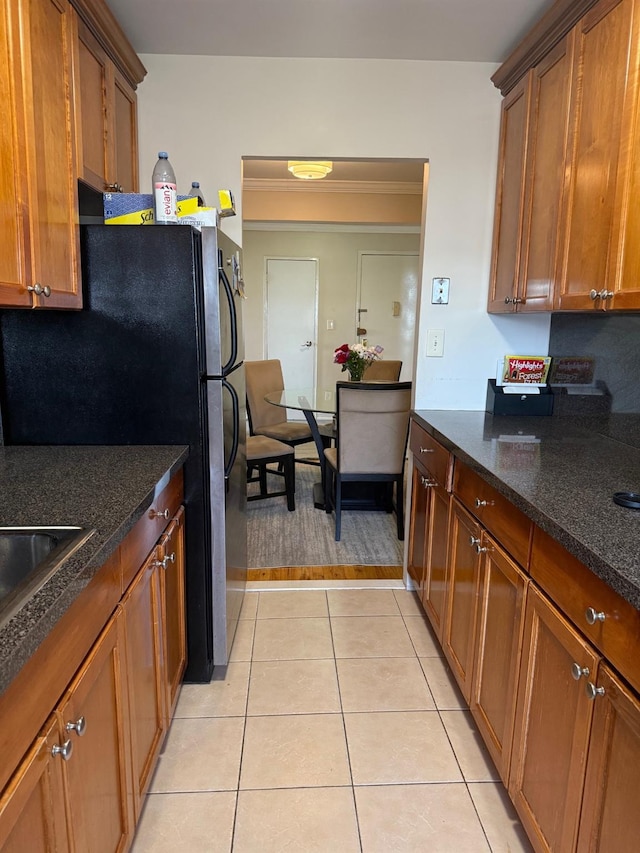 20 Wendell St Unit 9E, Hempstead, NY 11550 - kitchen with brown cabinets, light tile patterned floors, dark stone countertops, freestanding refrigerator, and ornamental molding