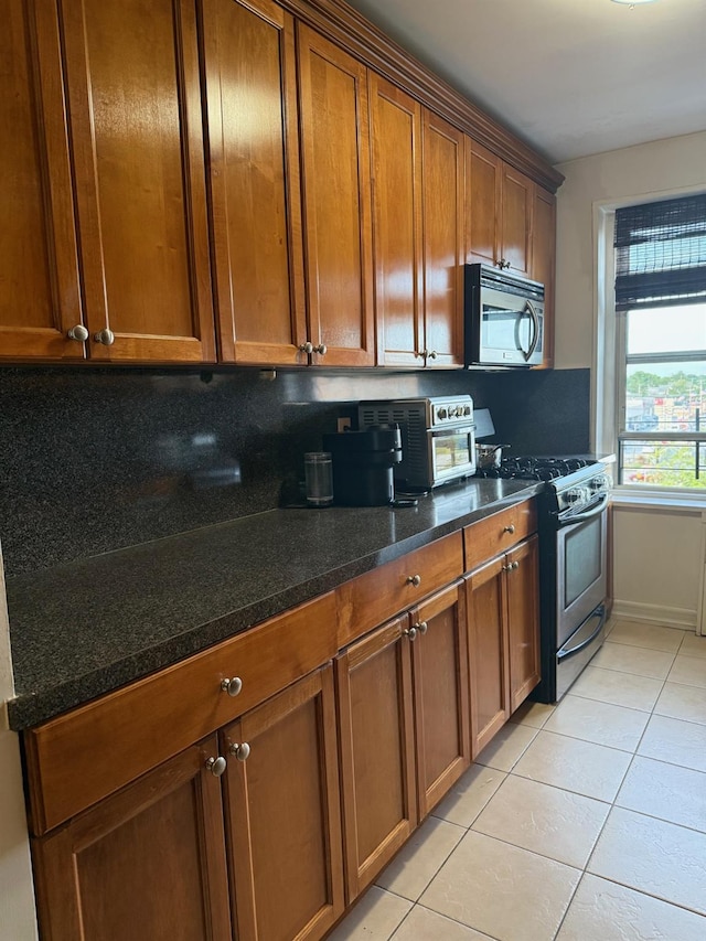 20 Wendell St Unit 9E, Hempstead, NY 11550 - kitchen featuring appliances with stainless steel finishes, light tile patterned floors, brown cabinets, and dark stone countertops