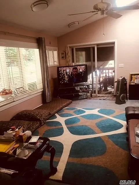 15 Oakhurst St, Huntington Station, NY 11746 - living room featuring ceiling fan, vaulted ceiling, and carpet flooring