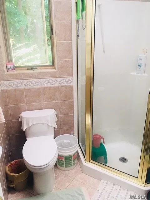 15 Oakhurst St, Huntington Station, NY 11746 - full bath with tile walls, tile patterned flooring, a stall shower, and toilet