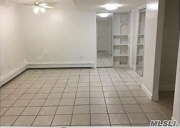 15 Oakhurst St, Huntington Station, NY 11746 - tiled spare room featuring ceiling fan, baseboards, and a baseboard heating unit