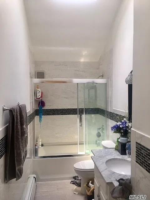 15 Oakhurst St, Huntington Station, NY 11746 - bathroom featuring shower / bath combination with glass door, vanity, toilet, and a baseboard radiator