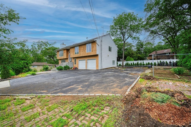 15 Oakhurst St, Huntington Station, NY 11746 - view of front of house featuring an attached garage, a chimney, and asphalt driveway