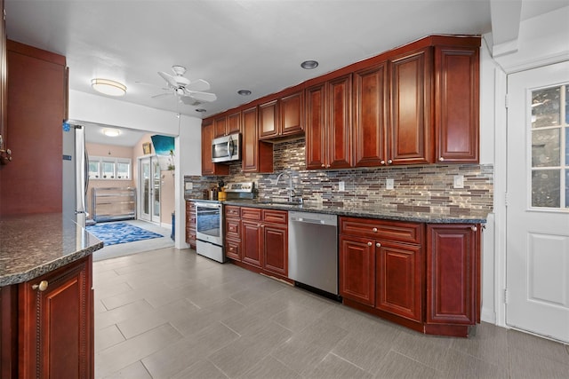 15 Oakhurst St, Huntington Station, NY 11746 - kitchen featuring reddish brown cabinets, appliances with stainless steel finishes, decorative backsplash, ceiling fan, and dark stone counters