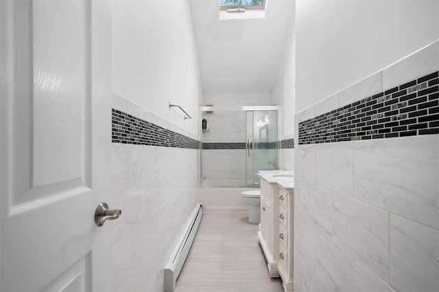 15 Oakhurst St, Huntington Station, NY 11746 - full bathroom with tile walls, a baseboard radiator, bath / shower combo with glass door, vanity, and wood finished floors