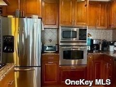 164-34 77th Ave, Fresh Meadows, NY 11366 - kitchen featuring stainless steel appliances, brown cabinets, and decorative backsplash