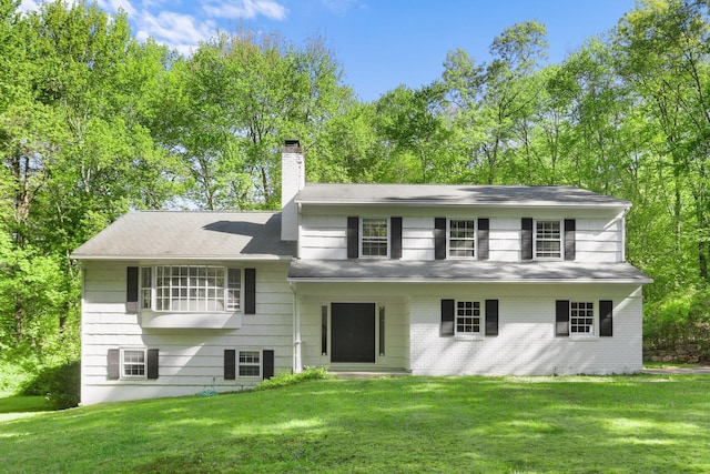 rear view of house featuring a chimney and a lawn